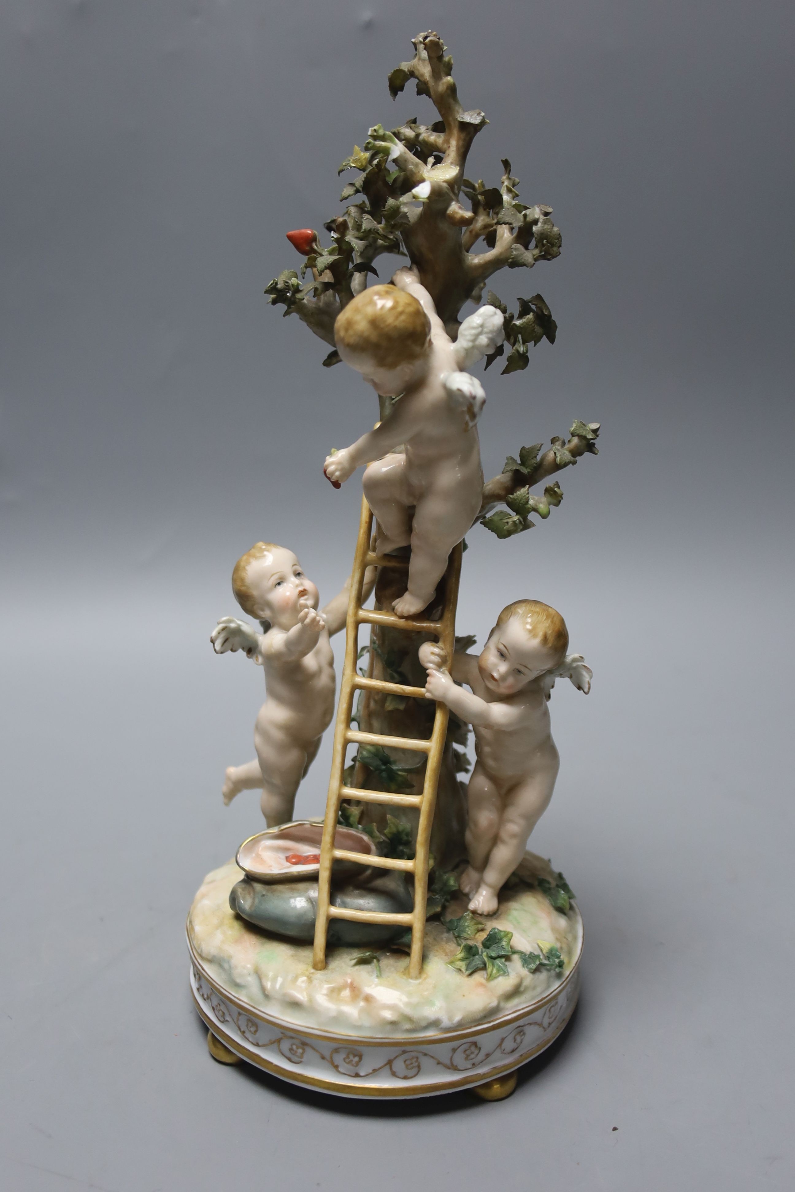 A German porcelain Meissen style group of amorini, climbing a ladder to pick fruit from a tree, small losses, 27cm